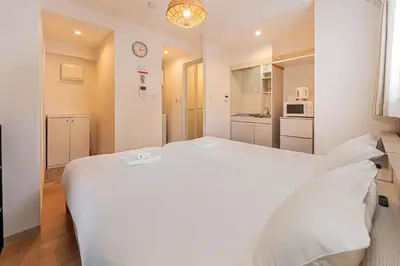 a bedroom with a large white bed and a kitchen at 67 Apartment Hotel Asakusa in Tokyo