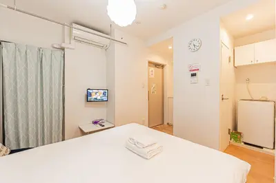a room with a white bed and a refrigerator at 67 Apartment Hotel Asakusa in Tokyo