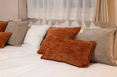 a white bed with brown pillows on it at All Good Stay KAMEARI in Tokyo