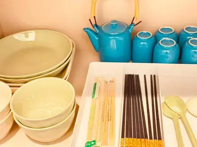 a shelf with plates and utensils and blue cups at Nexus Villa Morishita in Tokyo