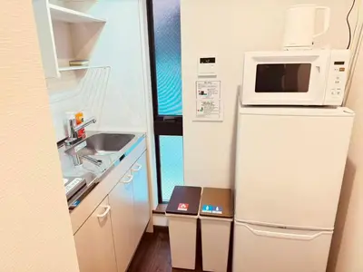 a kitchen with a microwave on top of a refrigerator at Nexus Villa Morishita in Tokyo