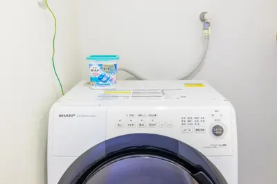 a washing machine with a container on top of it at HANEZORA HOTEL itabashi 2F in Tokyo