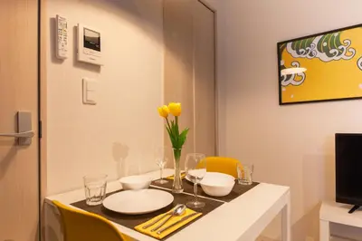 a dining room table with yellow chairs and a table with yellow flowers at Imb\u753a\u5c4b4\u4e01\u76ee301 in Tokyo