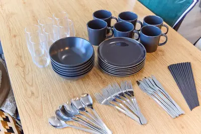 a table with plates and cups and forks and spoons at VORT Yamabukicho Residence in Tokyo