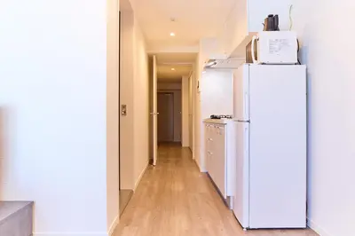 a kitchen with a white refrigerator and a hallway at VORT Yamabukicho Residence in Tokyo