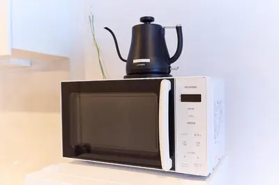 a microwave with a tea kettle on top of it at VORT Yamabukicho Residence in Tokyo