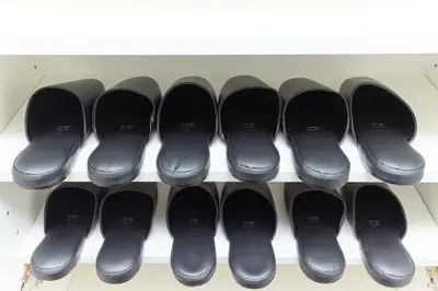 a row of black shoes on a shelf at VORT Yamabukicho Residence in Tokyo