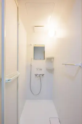 a white bathroom with a shower and a mirror at HANEZORA HOTEL itabashi 1F in Tokyo