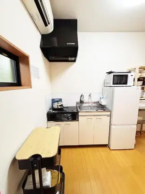 a small kitchen with a table and a refrigerator at TOKYONATIVES Kugahara Base in Tokyo