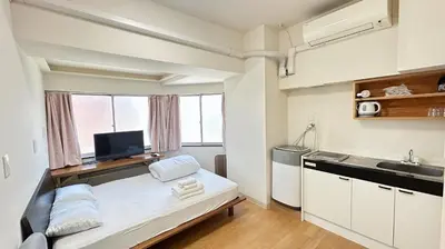 a small kitchen with a bed in a room at Skytree\u8eca\u7ad9\u5f92\u6b655\u5206 Tokyo\u6771\u4eac\u591c\u666f \u6a5f\u5834\u76f4\u9054 \u5e36\u5eda\u623f \u6d17\u8863\u6a5f \u96fb\u68af4 in Tokyo