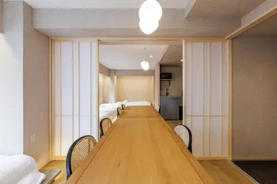 a long wooden table in a room with beds at 52A Kikyou NEW OPEN3 minutes from Ayase Station East Exit Modern Welcome to the family of students taking exams Private room rental 20 minutes to Ueno Asakusa in Tokyo