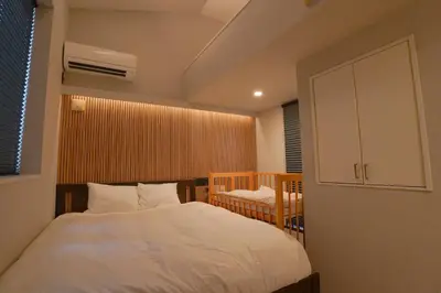 a bedroom with a bed and a cabinet and a chair at Besso Ebisu in Tokyo