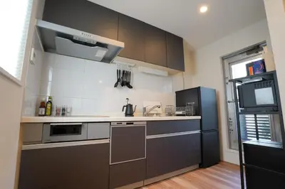 a kitchen with gray cabinets and a black refrigerator at Besso Ebisu in Tokyo