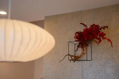 a vase filled with red flowers on a wall at Besso Ebisu in Tokyo