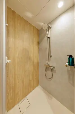 a shower in a bathroom with a wooden wall at 43 MatsuriNewly Opened 3 minutes from Ayase Station East Exit Jpanese modern Sophisticated space Private room Ueno and Asakusa 20 minutes in Tokyo