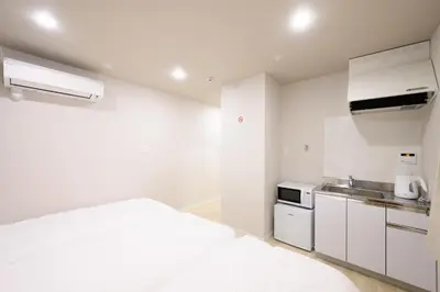 a white kitchen with a bed and a sink at Kohoku Apartment in Tokyo