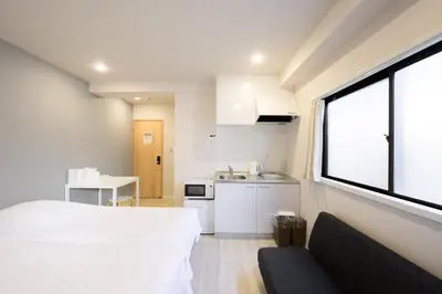 a bedroom with a bed and a kitchen with a window at Kohoku Apartment in Tokyo