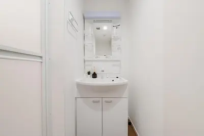 a white bathroom with a sink and a mirror at Alley Tateishi in Tokyo