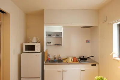 a small kitchen with a white refrigerator and a microwave at Negishi 301-TT0030 in Tokyo