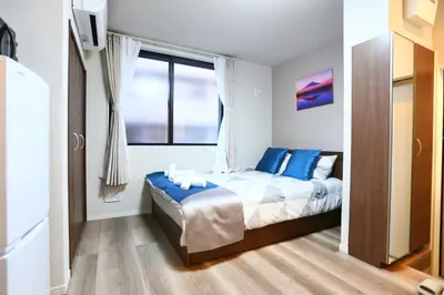 a bedroom with a bed with blue pillows and a window at 5 Min to Ikebukuro by Tobu Tojo Line I Oyama Private Suites in Tokyo