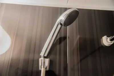 a shower head in a bathroom next to a curtain at iruka hotel 15 minutes to Shinjuku and Shibuya in Tokyo