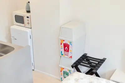 a small kitchen with a refrigerator and a black chair at Diamond Residences in Tokyo