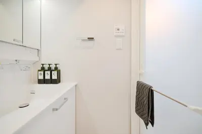 a white kitchen with bottles of wine sitting on a counter at Diamond Residences in Tokyo