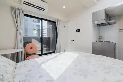 a white bedroom with a large bed and a window at Diamond Residences in Tokyo