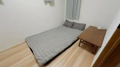 a small bed in a room with a wooden table at new open \u4e00\u6237\u5efa \u5bb6\u5ead \u591a\u4eba\u5165\u4f4f \u76f4\u8fbe\u4e0a\u91ce\u6d45\u8349 Skytree \u6210\u7530\u7fbd\u7530\u7a7a\u6e2f in Tokyo