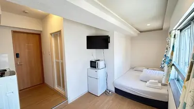 a small room with a bed and a microwave at Skytree\u8eca\u7ad9\u5f92\u6b655\u5206 Tokyo\u6771\u4eac\u591c\u666f \u6a5f\u5834\u76f4\u9054 \u5e36\u5eda\u623f \u6d17\u8863\u6a5f \u6709\u96fb\u68af4 in Tokyo