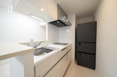 a kitchen with a sink and a black refrigerator at unito residence WASEDA West in Tokyo