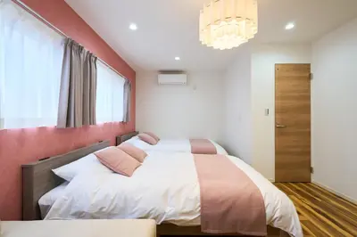 a bedroom with two beds and a chandelier at YAHIRO Base, 6m walk Yahiro Sta 94m2 2LDK Villa,3 Baths in Tokyo