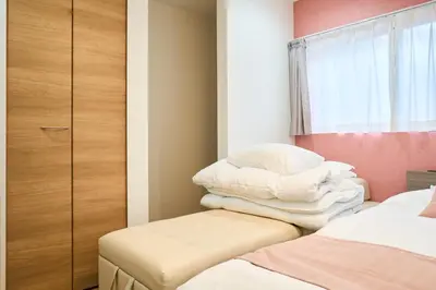 a room with a bed and a stack of pillows at YAHIRO Base, 6m walk Yahiro Sta 94m2 2LDK Villa,3 Baths in Tokyo
