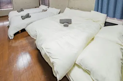 a group of three beds with white sheets and pillows at Living in a shopping street, 4DK, 10 people, skytree view, rooftop terrace in Tokyo