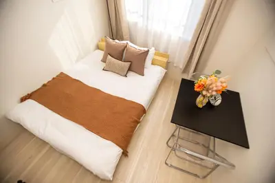a bedroom with a bed and a table with a vase of flowers at MIHOTEL Nakano- Shinjuku Direct in Tokyo