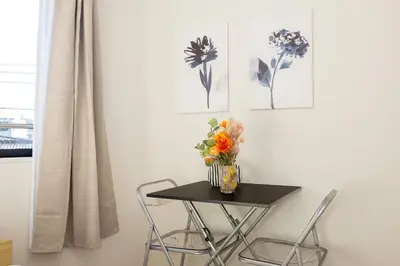 a table with chairs and a vase of flowers on it at MIHOTEL Nakano- Shinjuku Direct in Tokyo