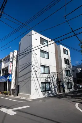 a white building on the corner of a street at MIHOTEL Nakano- Shinjuku Direct in Tokyo