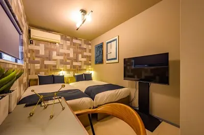a hotel room with two beds and a flat screen tv at Camo's Tokyo Asakusa in Tokyo
