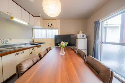 a kitchen with a long wooden table and leather chairs at SYLA HOTEL Akasaka in Tokyo