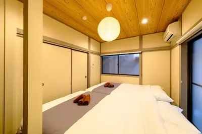 a bedroom with a large white bed with two slippers at \u30b3\u30af\u30a6 \u6771\u4eac\u90fd\u6e2f\u533a\u829d \u96a0\u308c\u5bb6\u7de8 in Tokyo