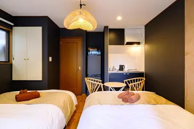 two beds in a room with a kitchen at \u30b3\u30af\u30a6 \u6771\u4eac\u90fd\u6e2f\u533a\u829d \u96a0\u308c\u5bb6\u7de8 in Tokyo
