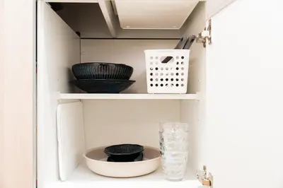 a cabinet filled with bowls and plates and a glass at Promotion Asakusa , 1 room, 8 mins to ST Max 2P \u8d85\u9ad8\u6027\u4ef7\u6bd4 \u6d45\u8349\u5168\u65b0\u88c5\u4fee \u8f66\u7ad98\u5206\u949f \u6700\u59272\u4eba in Tokyo