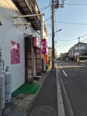 an empty street with a building with a green sidewalk at Jasnine House in Tokyo