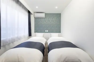 two beds in a room with a window at Hotel Kototoi East in Tokyo