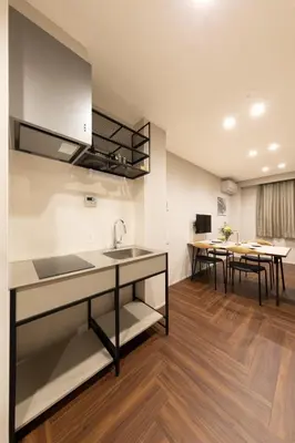 a kitchen with a sink and two tables in a room at Hotel Kototoi East in Tokyo