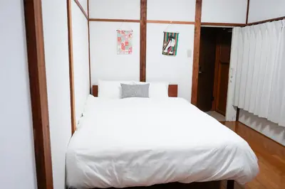 a bedroom with a bed with white sheets at Asakusa Hub Stay in Tokyo