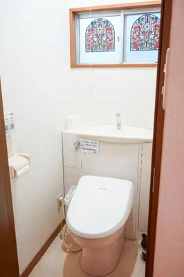 a bathroom with a toilet and a sink and two stained glass windows at Asakusa Hub Stay in Tokyo