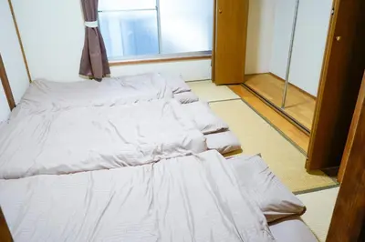 a row of white beds in a room at Asakusa Hub Stay in Tokyo