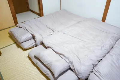 a large white bed with three pillows on the floor at Asakusa Hub Stay in Tokyo