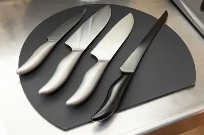 three knives sitting on a black plate on a counter at LINKAGE STAY Chitose Funabashi in Tokyo